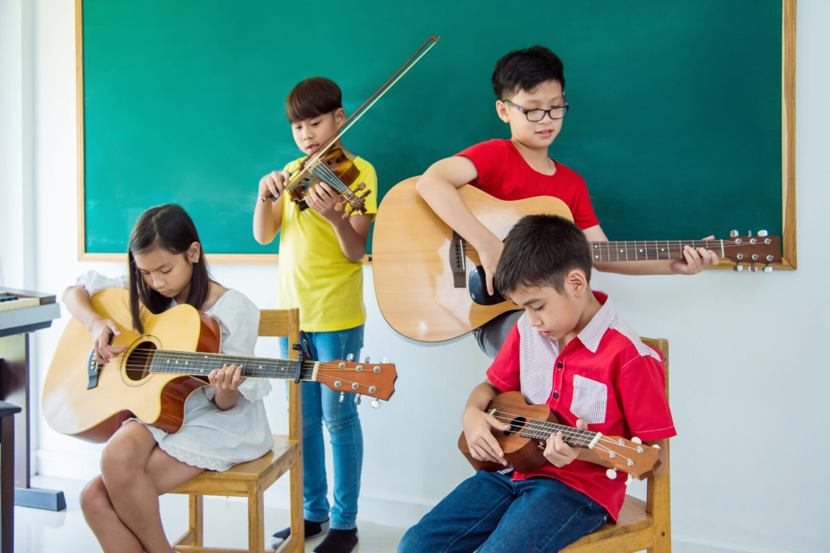Young asian children playing music instruments in music classroo