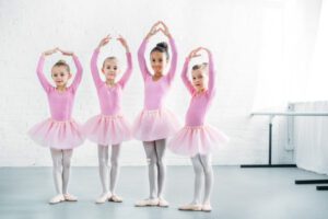 beautiful multiethnic kids in pink tutu skirts practicing ballet together